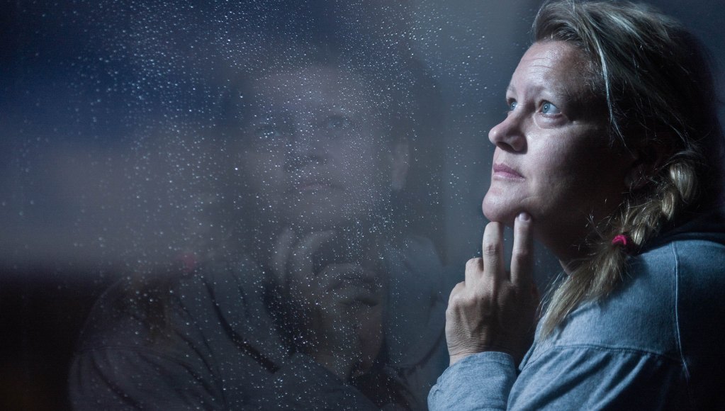 This image is here to match the topic and feelings associated with hitting rock bottom. It's of a woman within our ideal client target audience (over 40s) looking up and out a rainy window (looking up indicates hope).