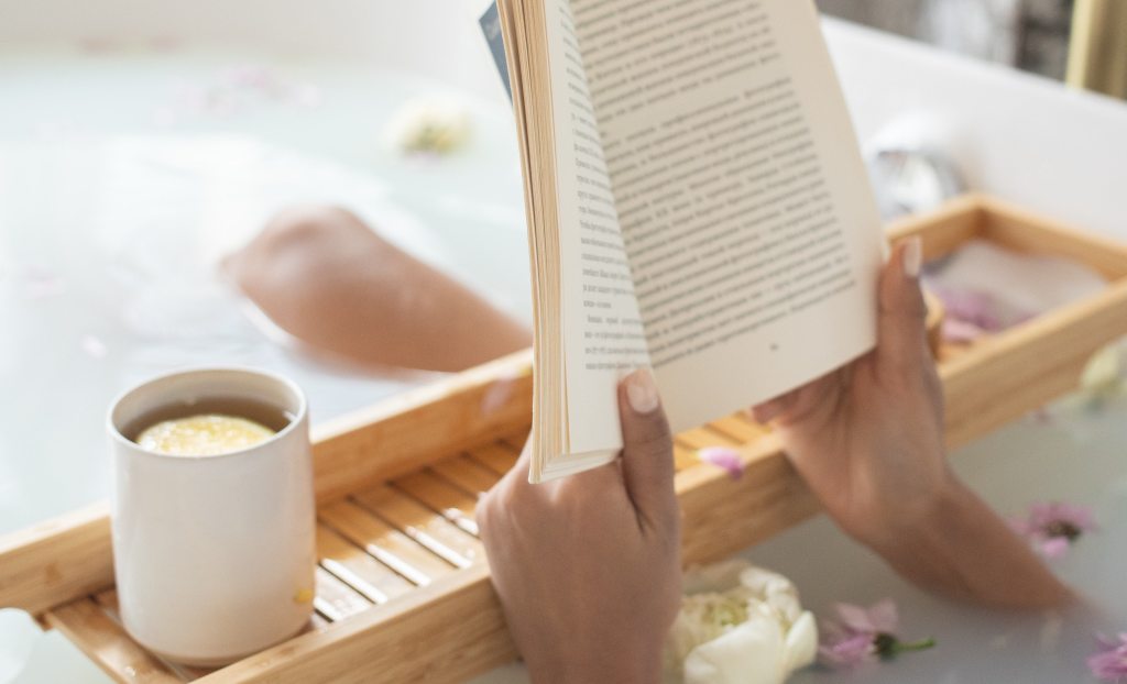 This photo of a woman reading a book and drinking coffee with flowers in the bath is to break up the paragraphs & to indicate someone taking care of themselves & their needs which is what the blog post is about. It's here for functionality purposes & decorative.